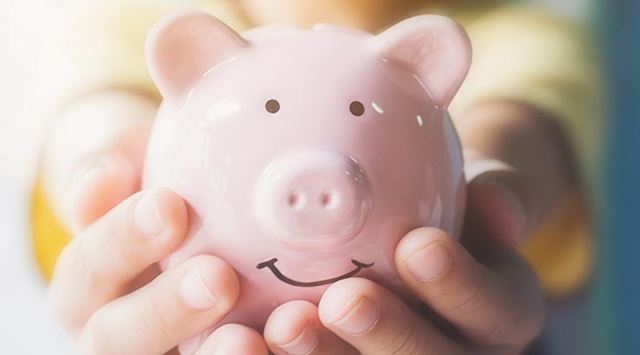 A person holding a pink piggy bank in their hands