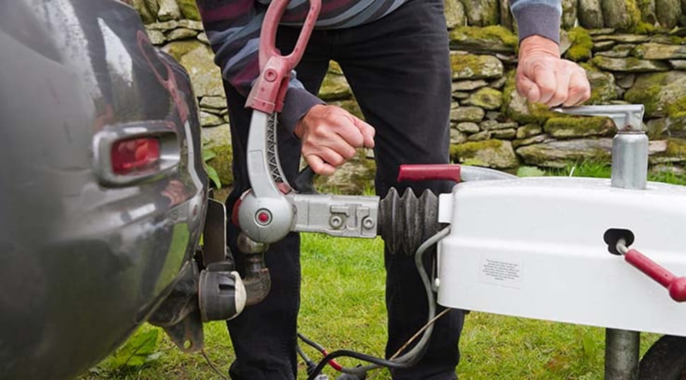 A man connecting a caravan to a tow bar