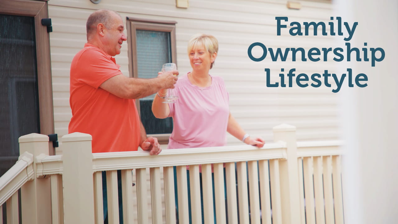 Man and woman clinking glasses on a veranda at Parkdean Resorts