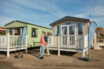 A couple exploring used caravans for sale on the showground at Parkdean Resorts