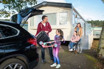 family loading car outside their caravan