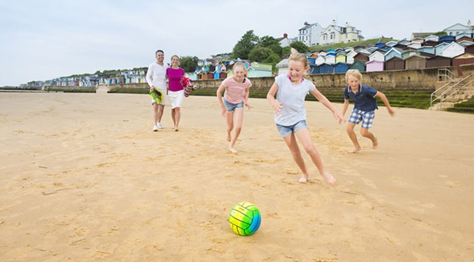 family playing football on a beach