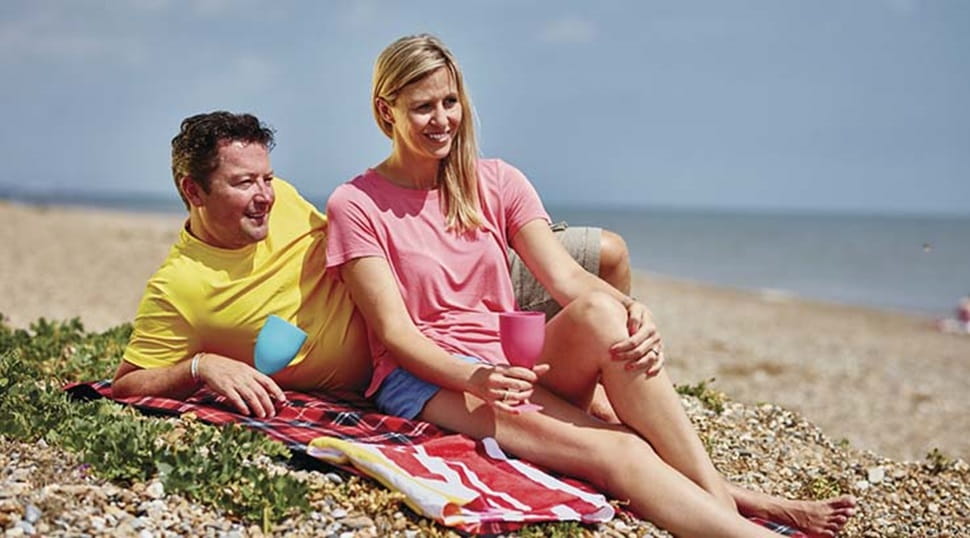 a couple sat on a picnic blanket on the beach