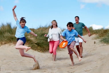 family running down sand dunes together