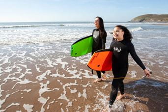 mother and daughter with paddleboards about to enter the sea