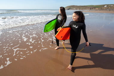 mother and daughter with paddleboards about to enter the sea