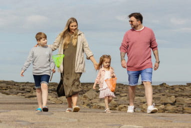 family walking down a sunny beach together