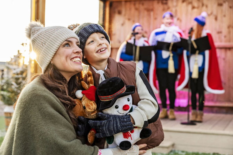 Mother and child watching carol singers on stage