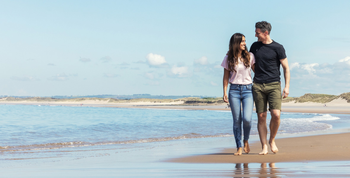 couple walking along a sunny beach