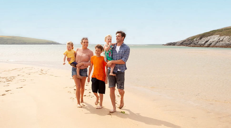 a family walking along the beach carrying the small children