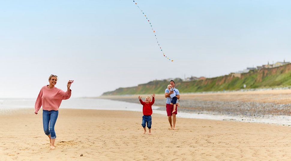 family flying a kite on a beach