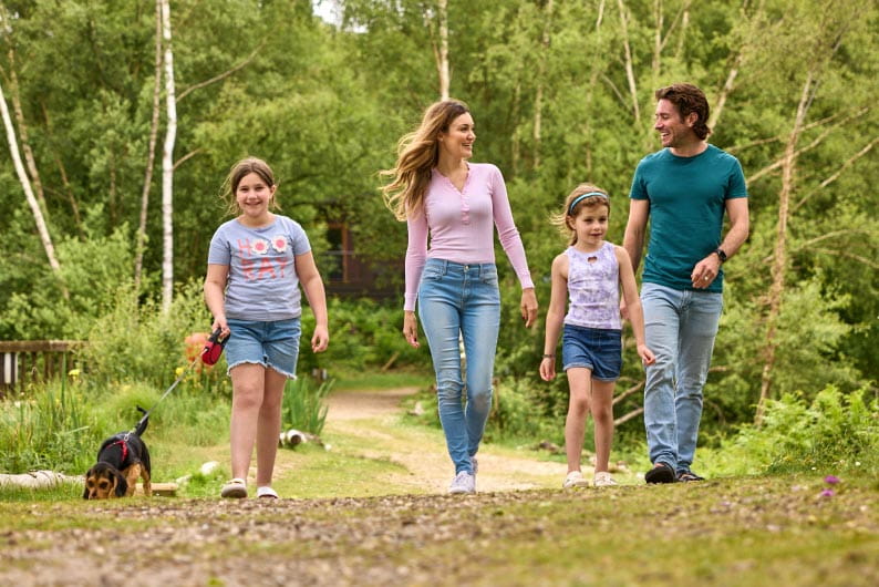Family walking with dog through woods