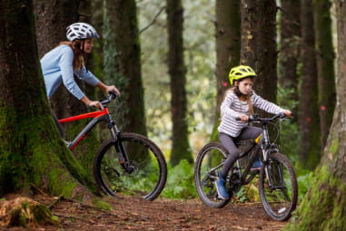 a woman and child cycling in the woods