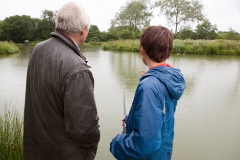 older man and younger boy fishing beside a lake