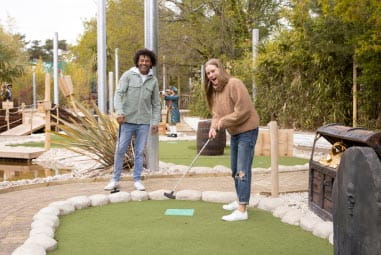 family playing crazy golf together outside