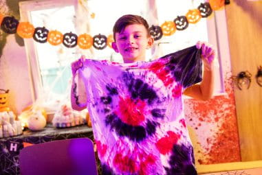 Child holding up tie dye shirt