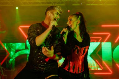 Performers singing on stage in Halloween costumes