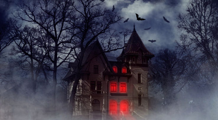 A haunted house in the woods surrounded by bats