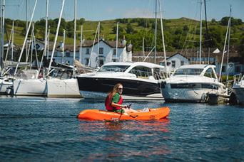A woman kayaking around Bowness marina in the Lake District