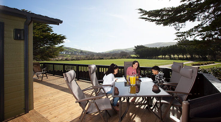Family relaxing around a table on a lodge veranda on a sunny day