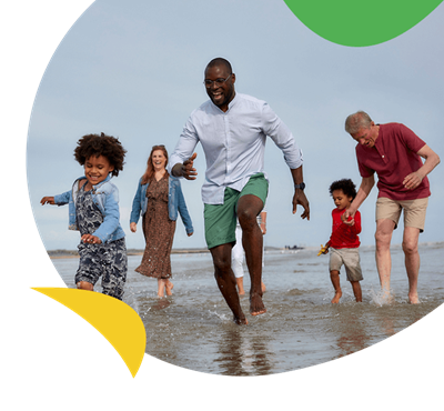 A family and grandparents paddling on the beach