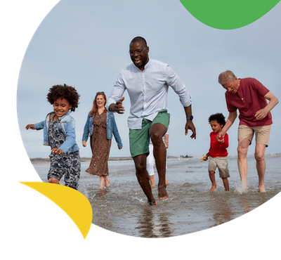 A family and grandparents paddling on the beach