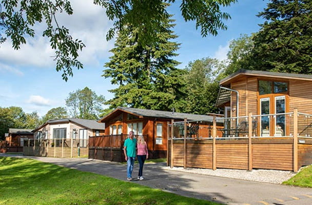 A couple walking through lodges on a holiday park in the Lake District