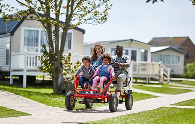 A family exploring the holiday park on a pedal kart