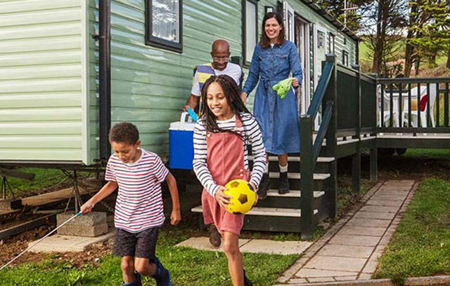 A family exiting their caravan carrying beach equipment