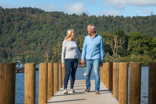 older couple walking down lake boardwalk