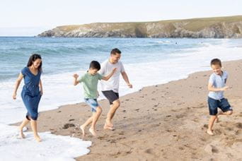 a family running near the water on a picturesque beach