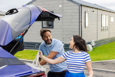 father and daughter loading their car beside a caravan