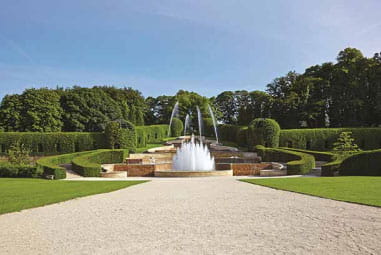 beautiful picture of Alnwick Garden with lush green trees and grand waterfall