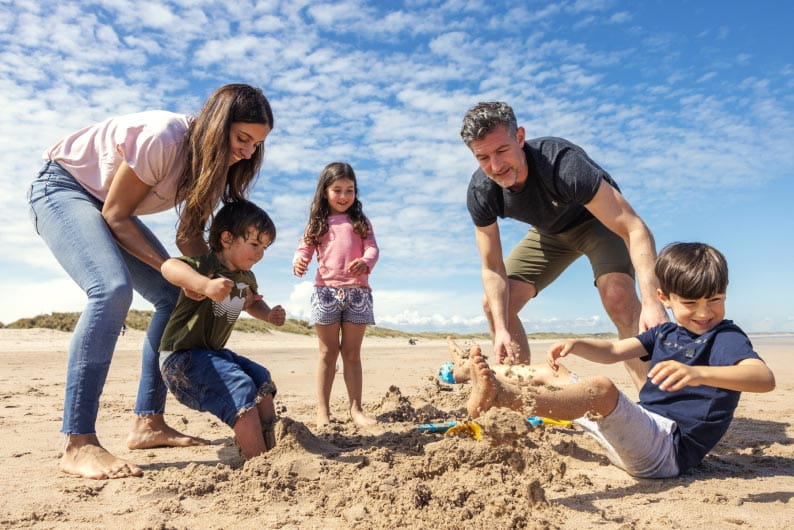 family digging in the sand on a beach