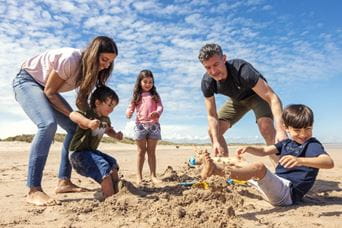 family digging in the sand on a beach