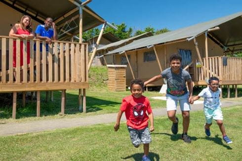 Family running outside glamping pod at Parkdean Resorts