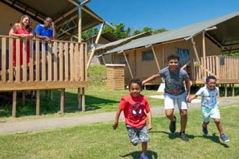 Family running outside glamping pod at Parkdean Resorts