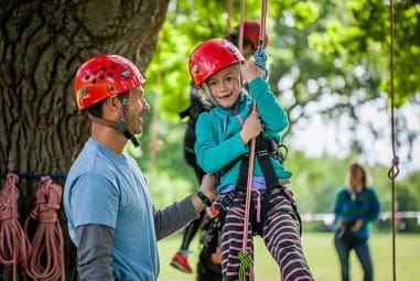 Little girl wearing red helmet on a rope swing