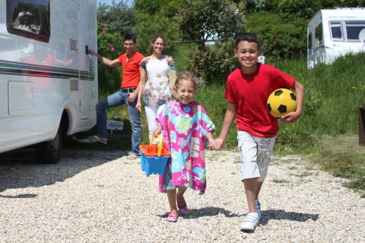 Kids running hand in hand towards the beach with a yellow football