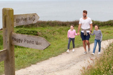 Dad walking hand in hand with children along the beach