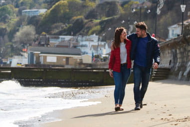 Couple walking along the beach cuddling