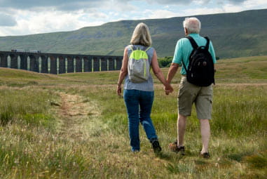 Couple walking hand in hand with back packs on back