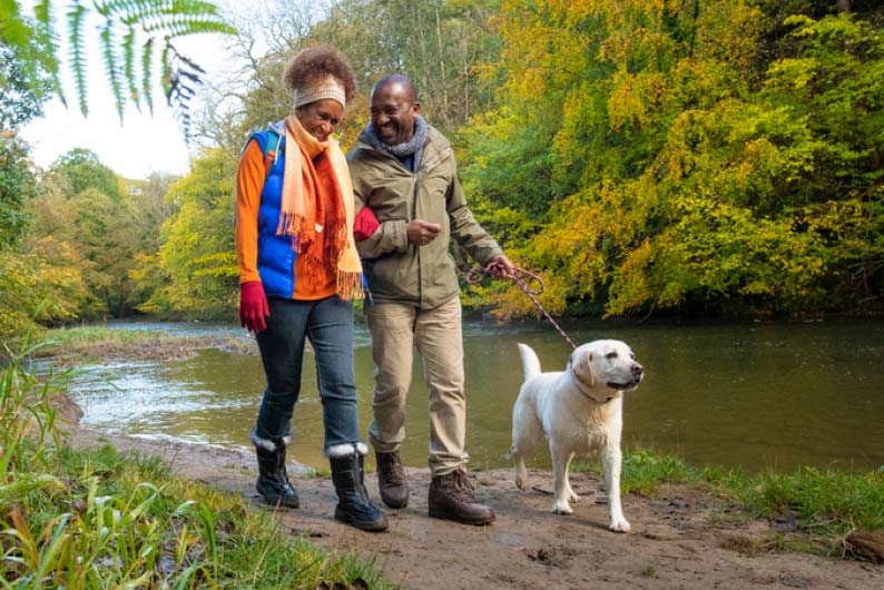 Couple walking with pet dog along the river