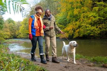 Couple walking with pet dog along the river