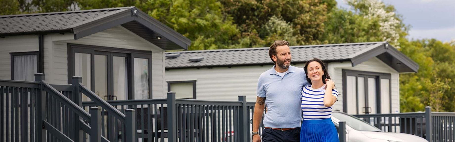 A couple walking past a row of caravans in a holiday park