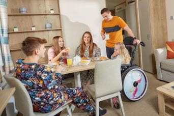A family with a family sits around a table in a wheelchair accessible caravan