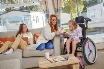 A young girl in a wheelchair and her family relax in a spacious accessible lodge
