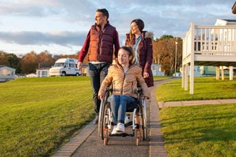 A girl in a wheelchair and her family outdoors at a Parkdean resort