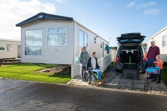 A family which includes a wheelchair user unpacks outside an accessible caravan
