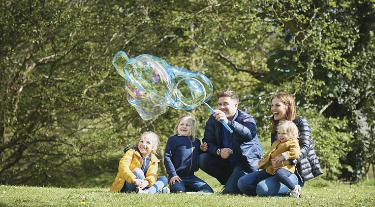 a family sat on grass blowing large bubbles